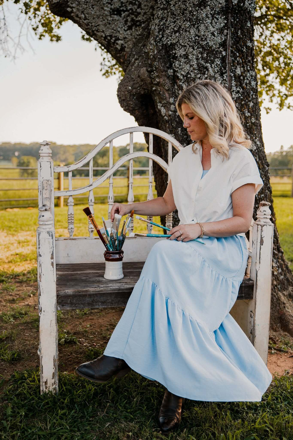 

Mindi seated outdoors beside a small vase of flowers.