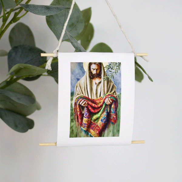 Mini collectible art of Jesus holding a multicolored coat, inspired by Joseph’s robe — Garment of Promise by Mindi Oaten, hanging with natural twine.