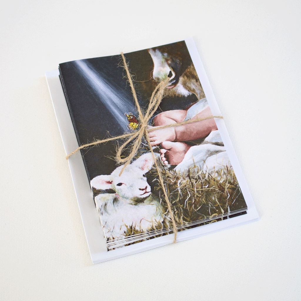Set of Immanuel Christmas note cards by Mindi Oaten, featuring baby Jesus with a lamb and a butterfly, tied with natural twine — blank Christian art cards.