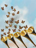 

A Call to Renaissance by Mindi Oaten, showing golden trumpets beneath rising monarch butterflies against a blue sky.