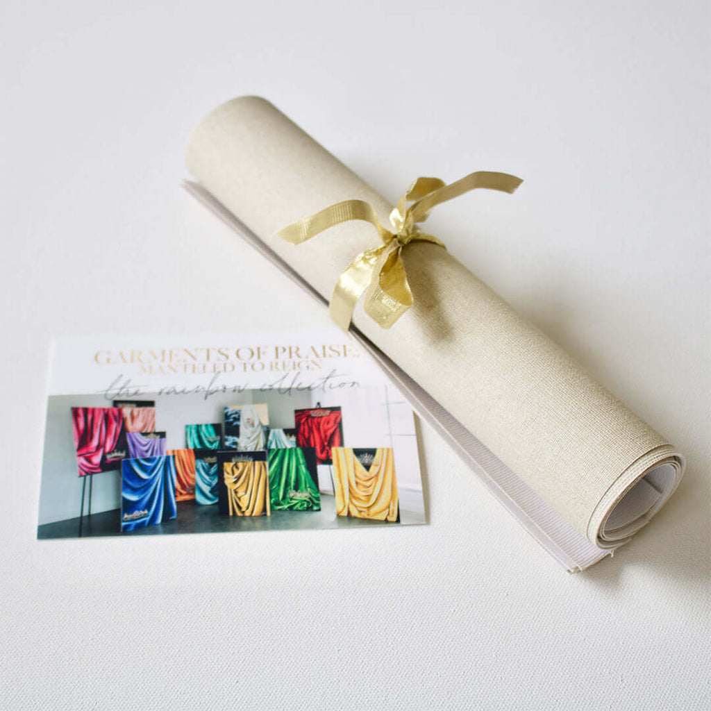 

A canvas roll tied with a gold ribbon beside an information card.