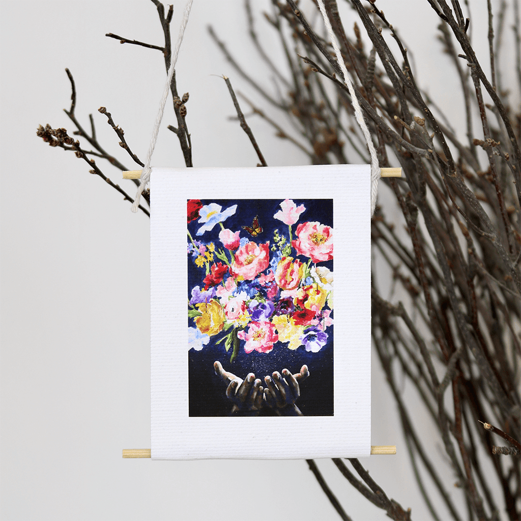 

A Garden of Prayer by Mindi Oaten: a small hanging floral artwork with raised hands.
