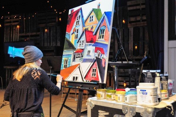 

Mindi painting colorful houses at an easel during a live event.