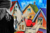 

Mindi painting colorful houses at an easel during a live event.