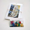 

A bundled paper print set tied with twine beside an information card.